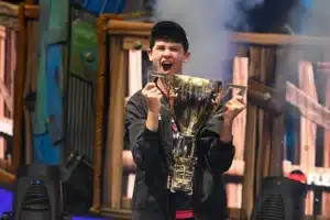 Fortnite Dünya Kupası şampiyonu Bugha büyük altın kupayı kaldırarak sevinç çığlığı atıyor.